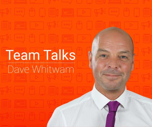 Employee in a white shirt with purple tie against an orange background