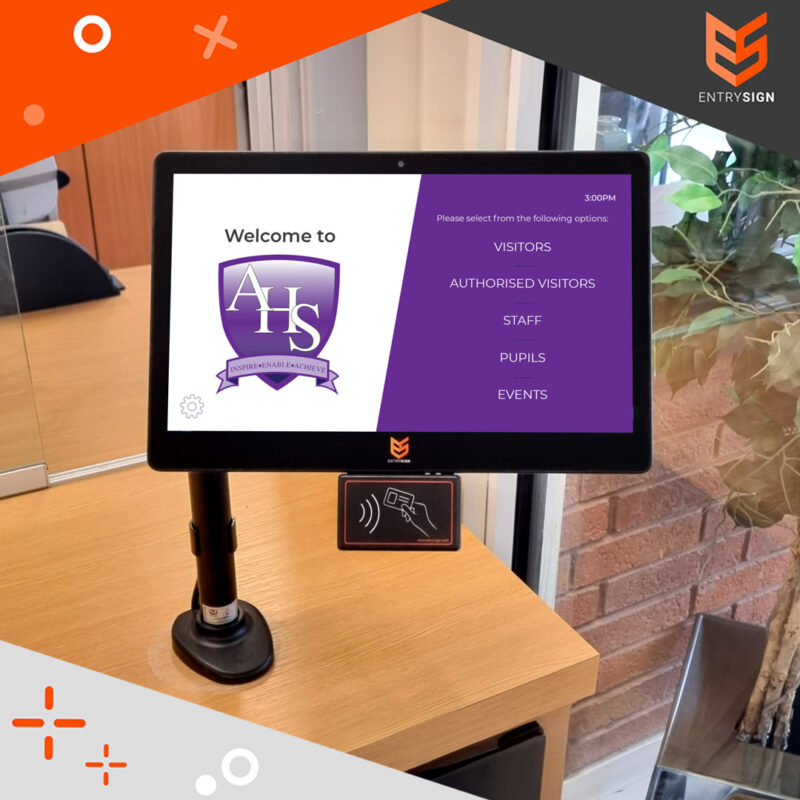 School visitor management screen with purple and white user interface on a wood table.