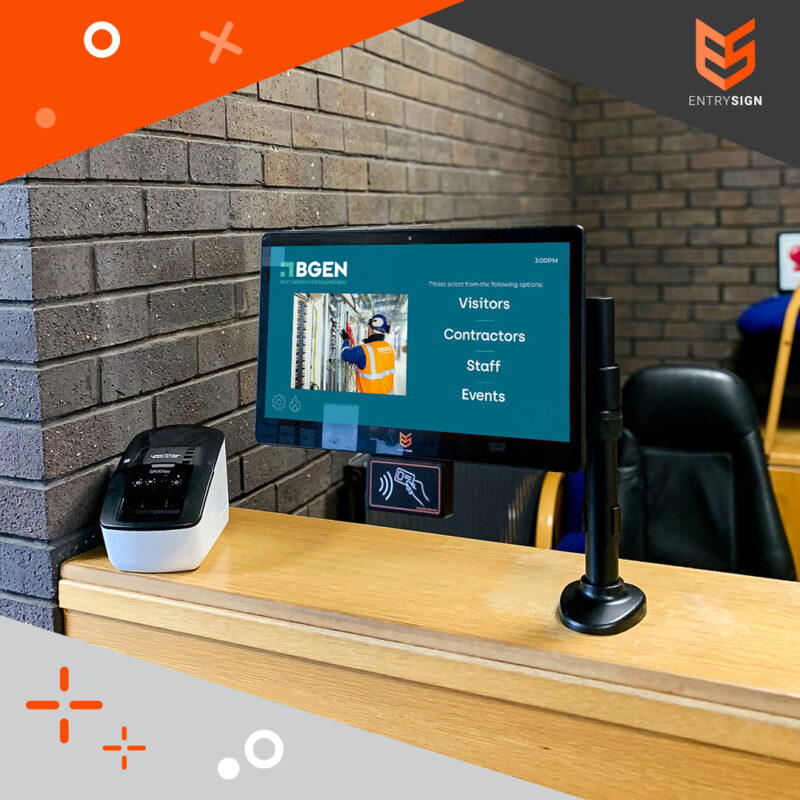 Visitor management screen with a turquoise user interface and installed on a wood desk.