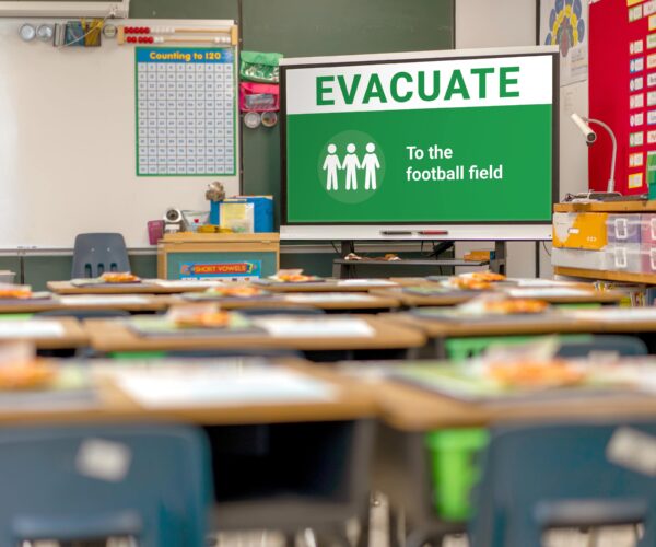 Screen in a school classroom with signage to evacuate