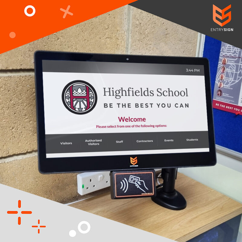 School visitor management screen on an oak desk with grey and white user interface.
